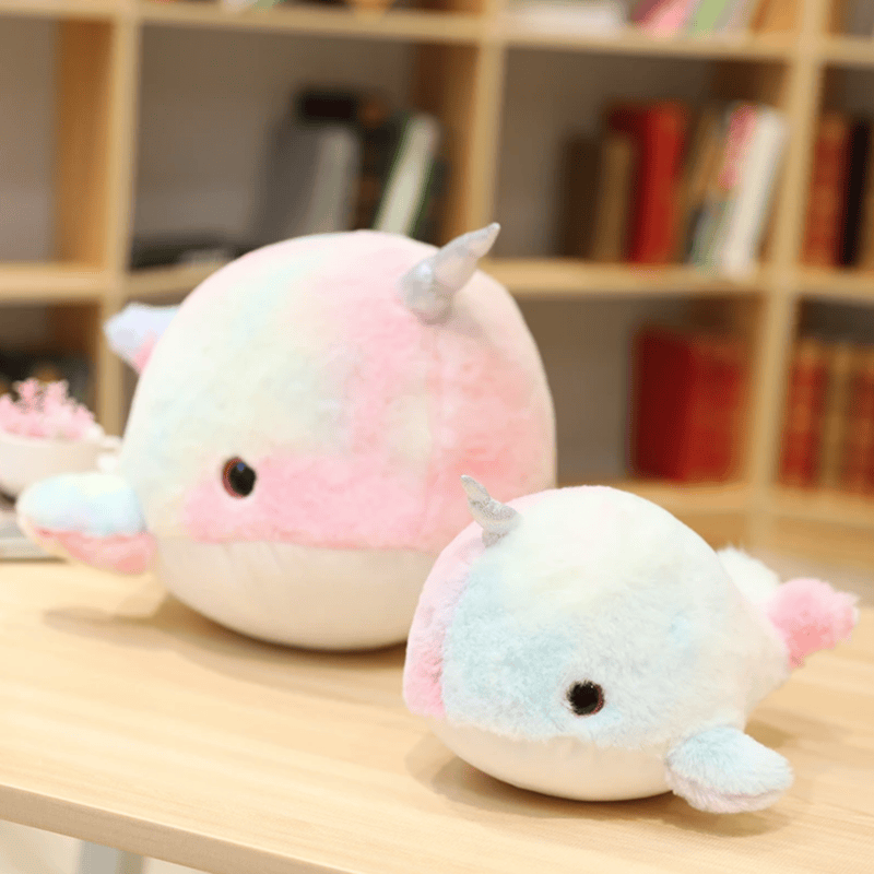 Deux peluches baleine rose licorne poses sur une table
