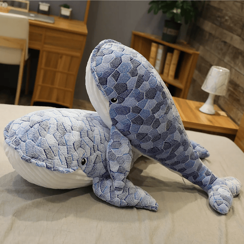 Deux peluches baleines écailles posé sur un lit Image