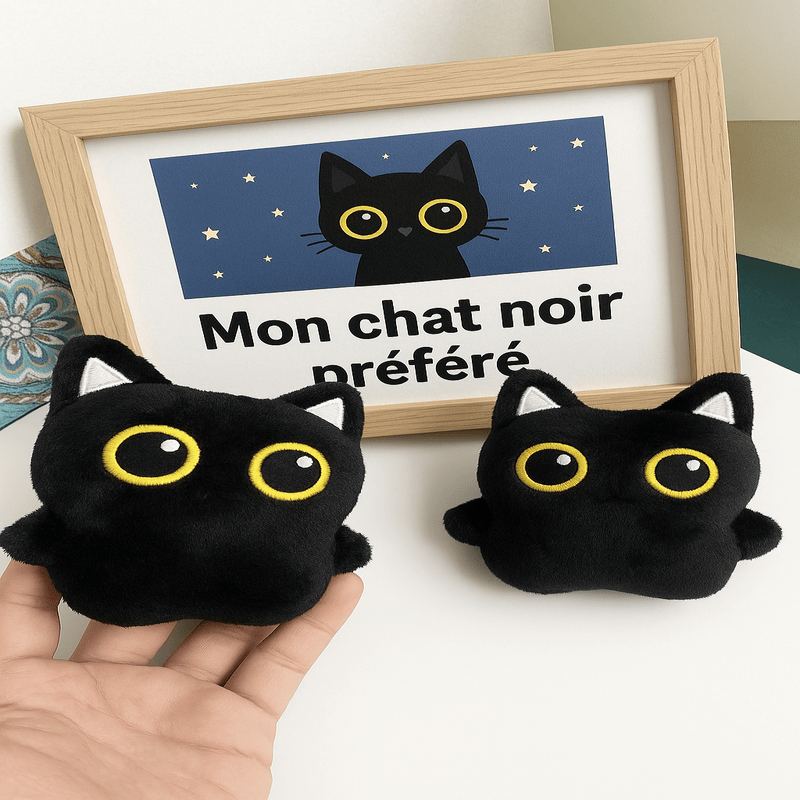 Petit chat noir en peluche à côté d'une autre peluche chat noir