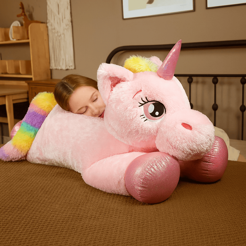 Peluche licorne rose sur un lit avec une fille