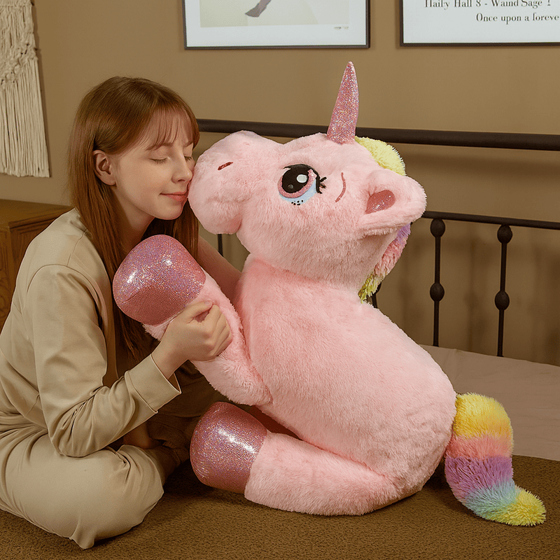 Peluche licorne rose sur un lit avec une fille