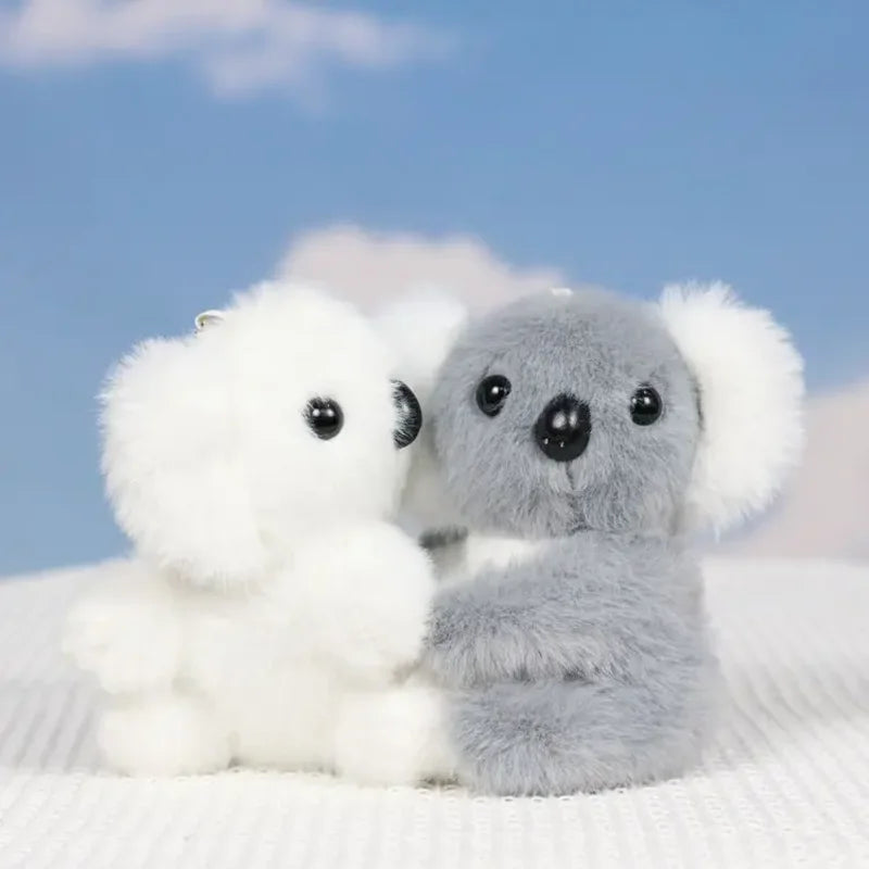 Deux mini peluches koala blanc et gris sur un drap dont un qui tourne la tête Image