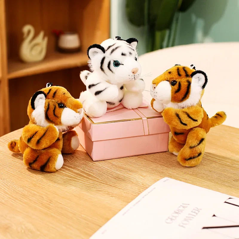 Trois mini peluches tigres sur une table et une peluche sur une boite à bijoux