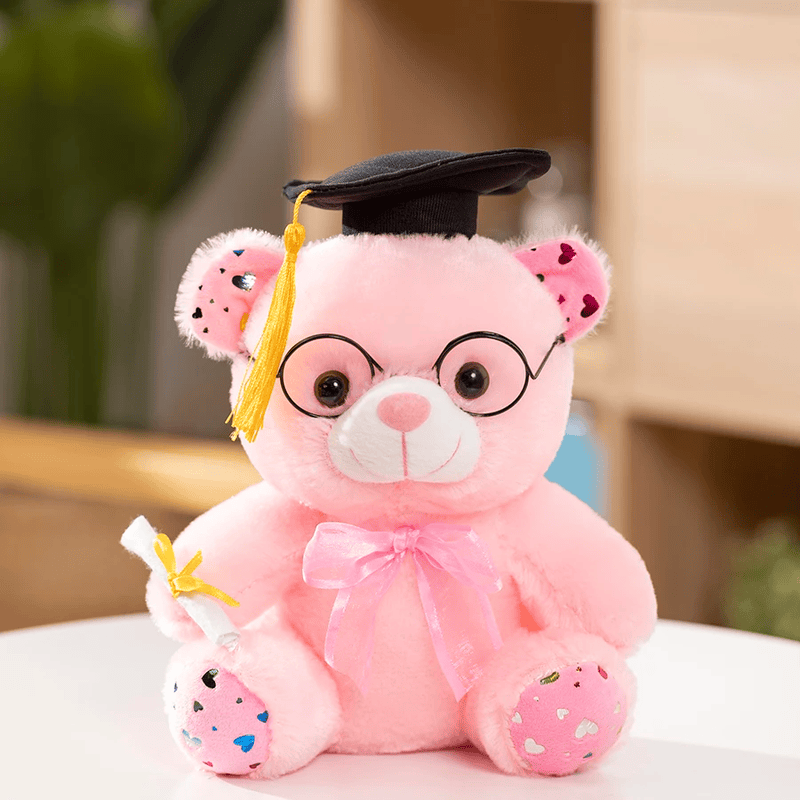 Ours rose en peluche diplômé sur une table blanche Image