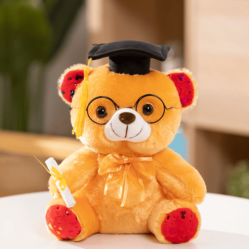 Ours orange en peluche diplômé sur une table blanche