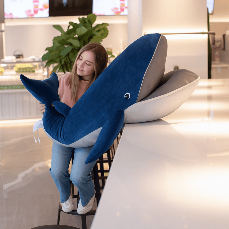 Peluche baleine bleue nordique poser sur les genoux d'une fille