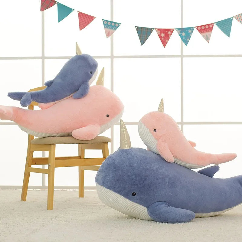 Quatre peluches baleines licorne sur un tapis et sur une chaise Image