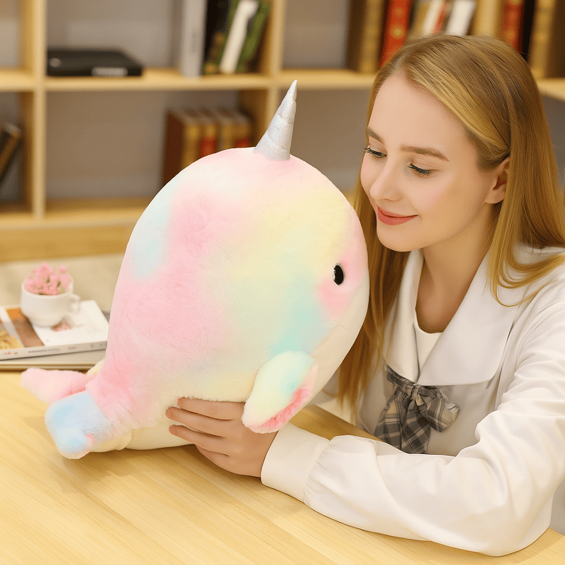 Une peluche baleine licorne multicolore tenue par une fille 