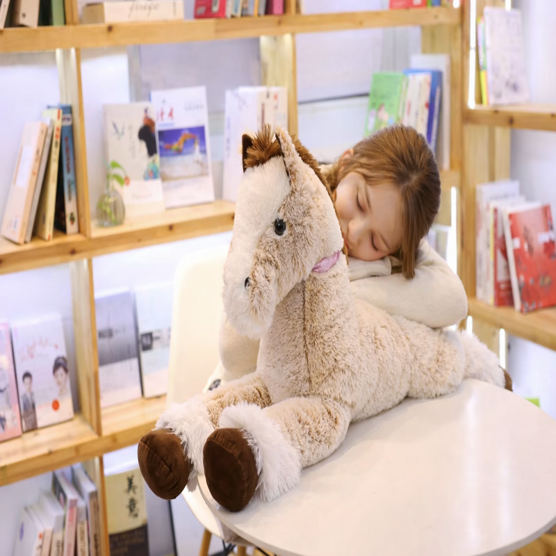Peluche cheval posée à plat ventre sur une table avec une fille endormi dessus Image