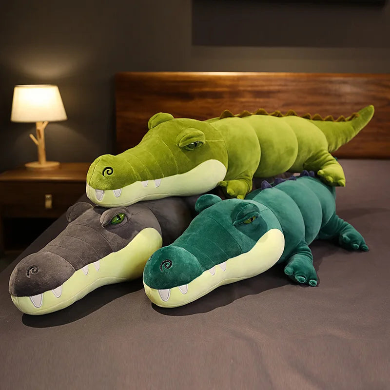 Trois peluches crocodiles xxl sur un lit entassé sur eux même Image