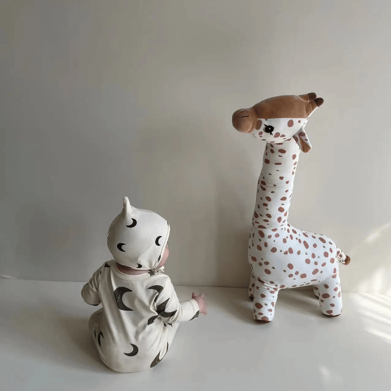 Peluche girafe blanche debout devant un bébé Image