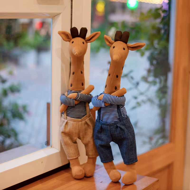 Deux peluches girafes habillées sur un meuble Image