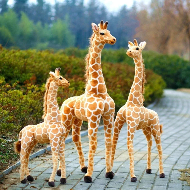 Trois peluches girafes xxl dans la nature sur des pavés