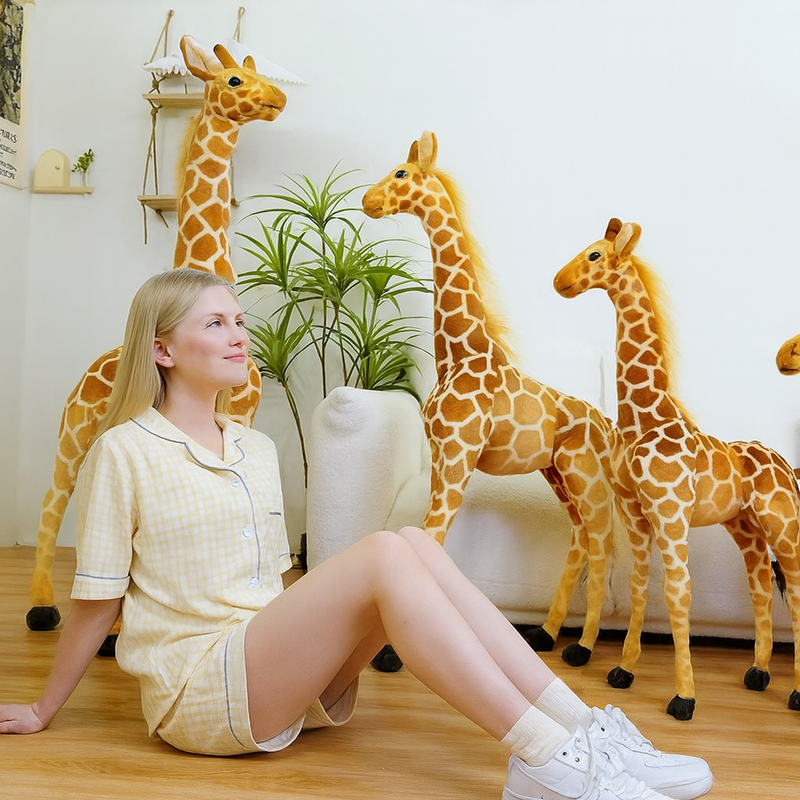 Trois peluches girafes xxl avec une fille assise devant un canapé