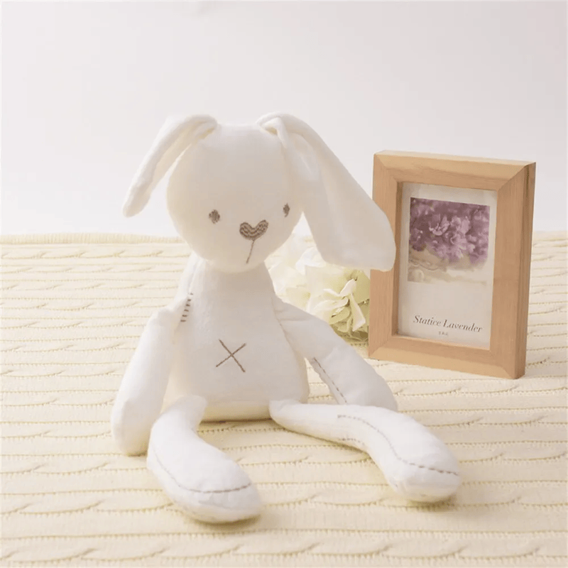 Peluche lapin compagnon de couchage, assis sur un matelas