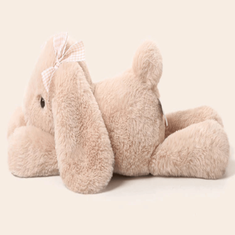 Peluche lapin couché de profile sur un fond blanc