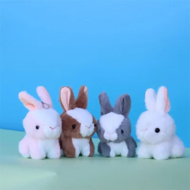 Quatre peluches lapins nains sur un terrain vert