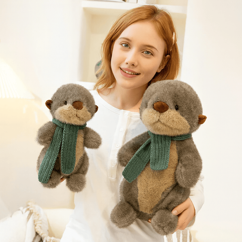 Deux peluches loutres avec leurs écharpes dans les bras d'une fille Image