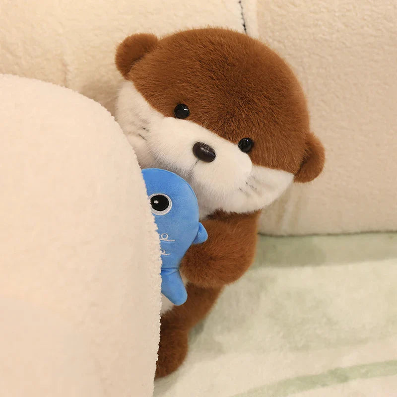 Peluche loutre avec son poisson Kawaii derrière un coussin