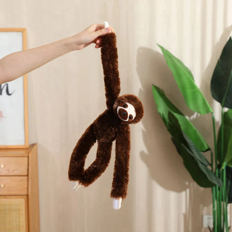 Peluche paresseux brun tenue par une main par une fille