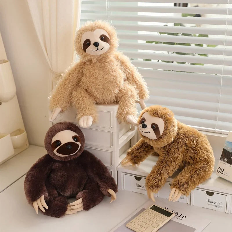 Trois peluches paresseux heureux sur un meuble