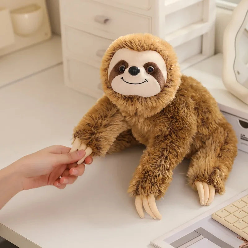 Peluche paresseux brun heureux sur un meuble tenu par la main d'une fille
