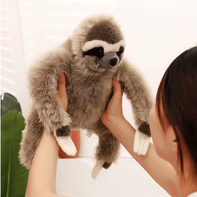 Peluche paresseux réaliste tenu par une fille par les mains 