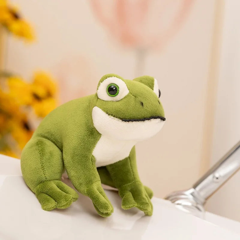 Peluche petite grenouille sur une table blanche inclinée