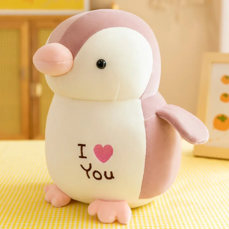 Peluche pingouin rose I love you sur une table avec une nappe à carreaux jaune et blanc