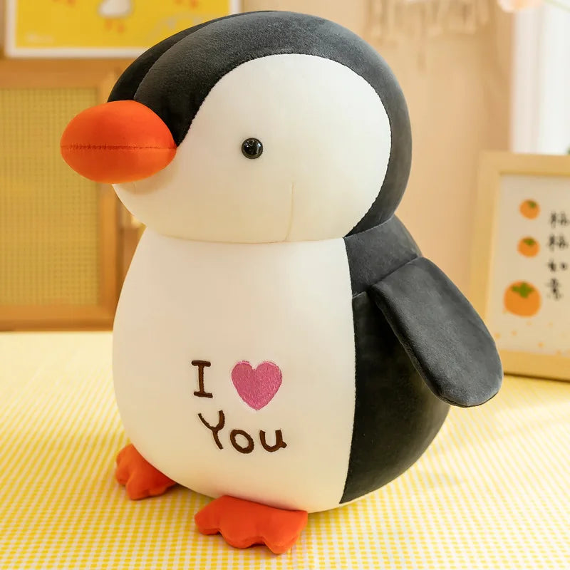 Peluche pingouin noir I love you sur une table avec une nappe à carreaux jaune et blanc