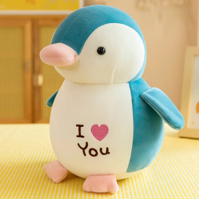 Peluche pingouin vert I love you sur une table avec une nappe à carreaux jaune et blanc