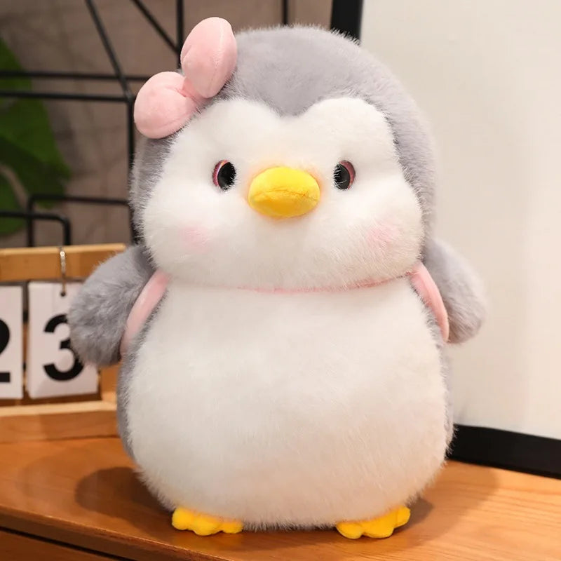 Peluche pingouin avec un sac à dos rose sur une table