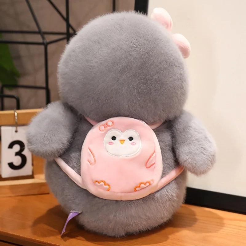 Peluche pingouin avec un sac à dos rose sur une table