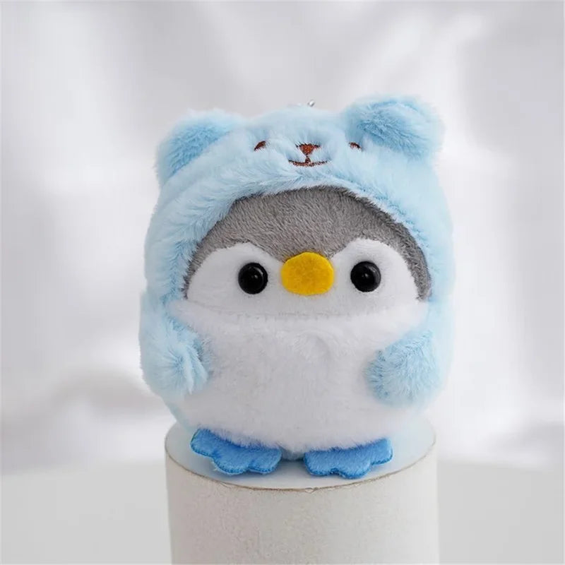 Peluche pingouin avec une capuche d'ours bleue sur un bâtonnet