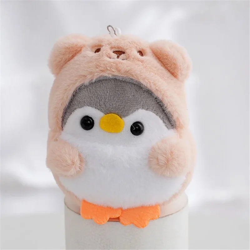 Peluche pingouin avec une capuche d'ours orange sur un bâtonnet