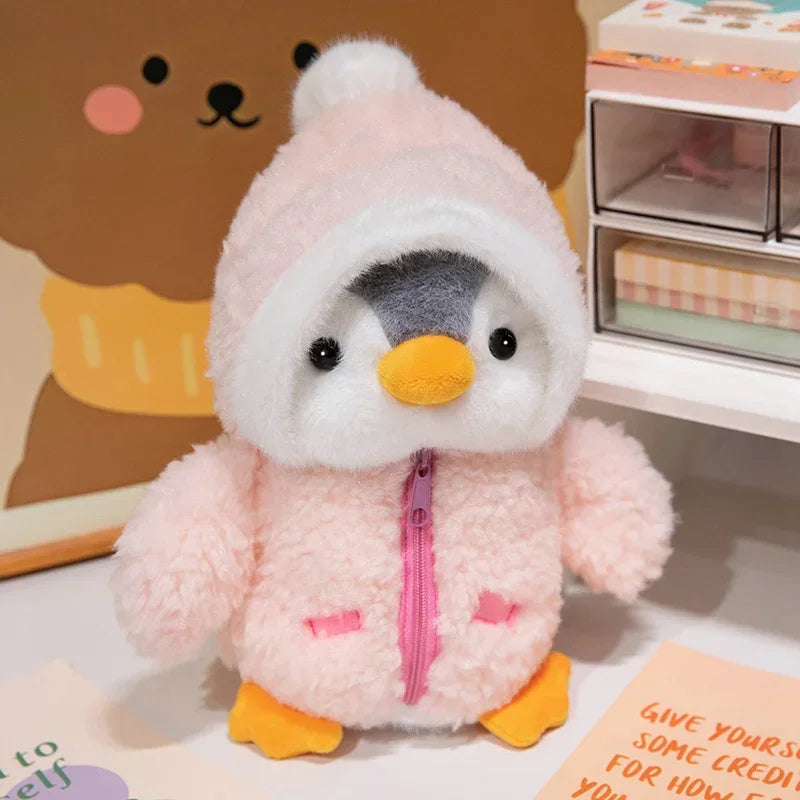 Peluche pingouin avec une doudoune rose sur une table