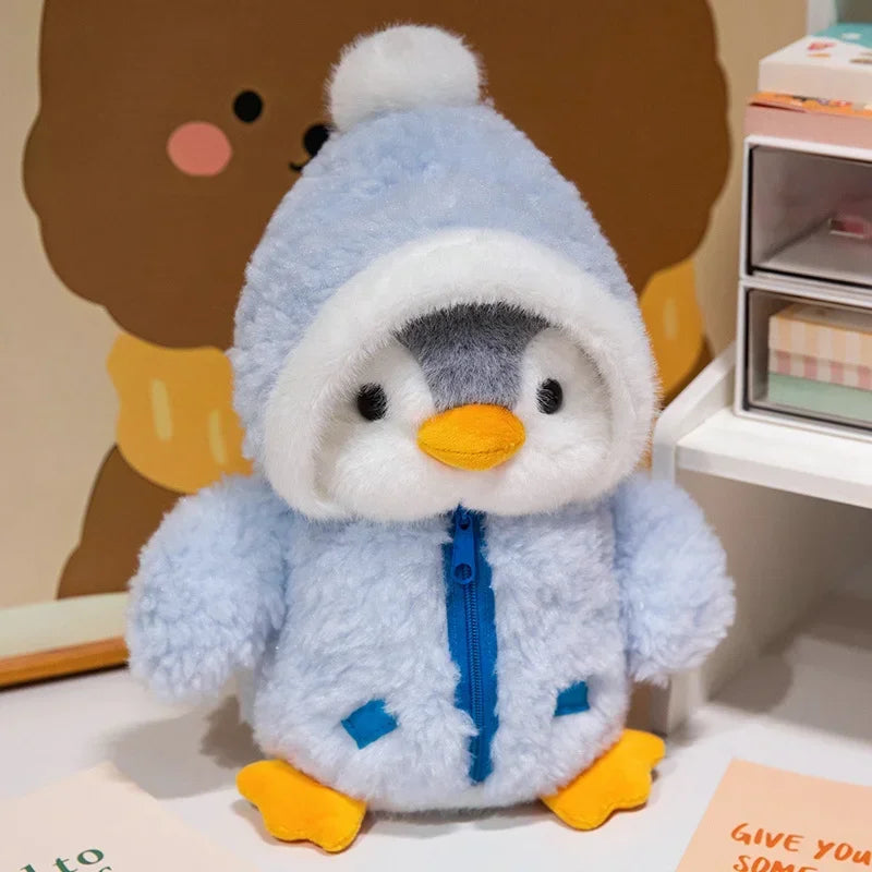 Peluche pingouin avec une doudoune bleue sur une table