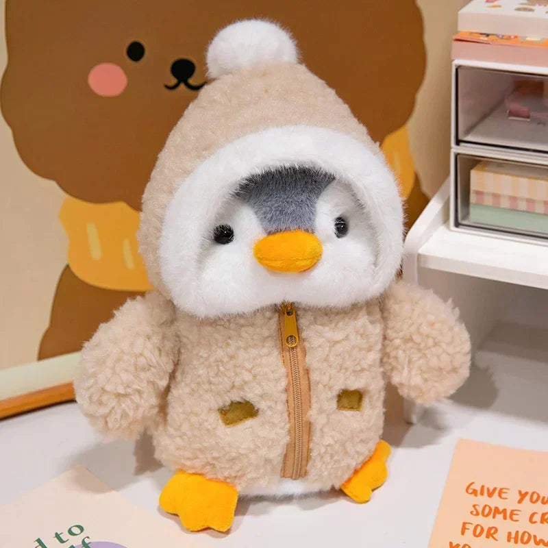 Peluche pingouin avec une doudoune marron sur une table