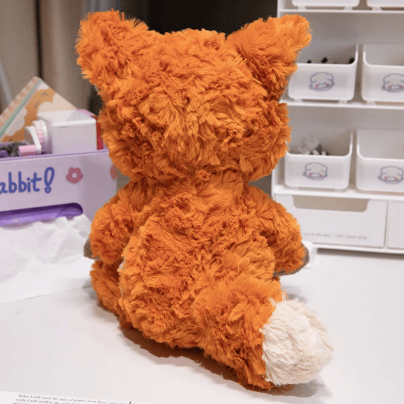 Peluche renard câlin de dos sur une table blanche