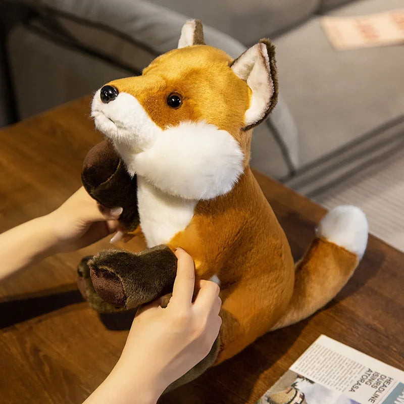 Peluche renard domestique sur une table bois tenu par une fille par les pattes 