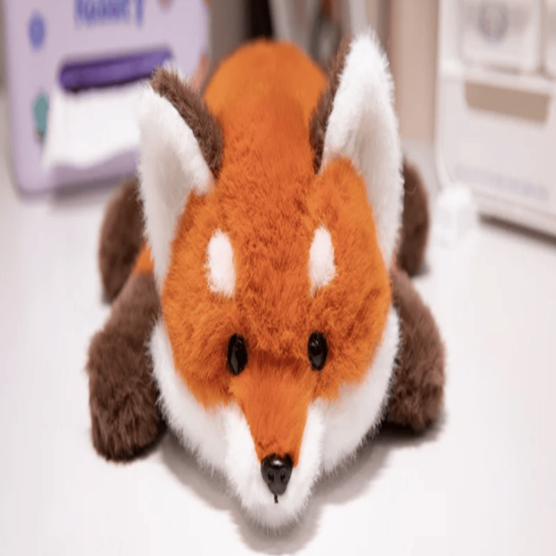 Peluche renard douce couché sur un bureau blanc