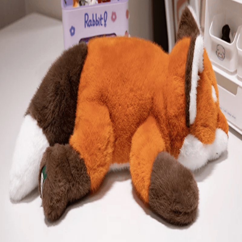 Peluche renard douce couché de profil sur une table blanche