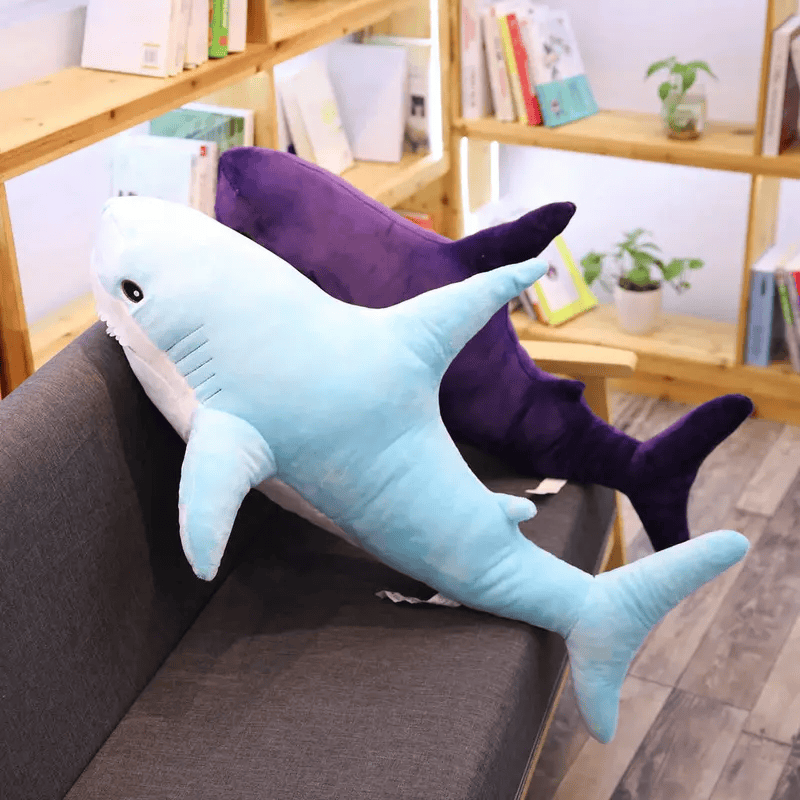 Deux peluches requins bleu et violet sur un canapé