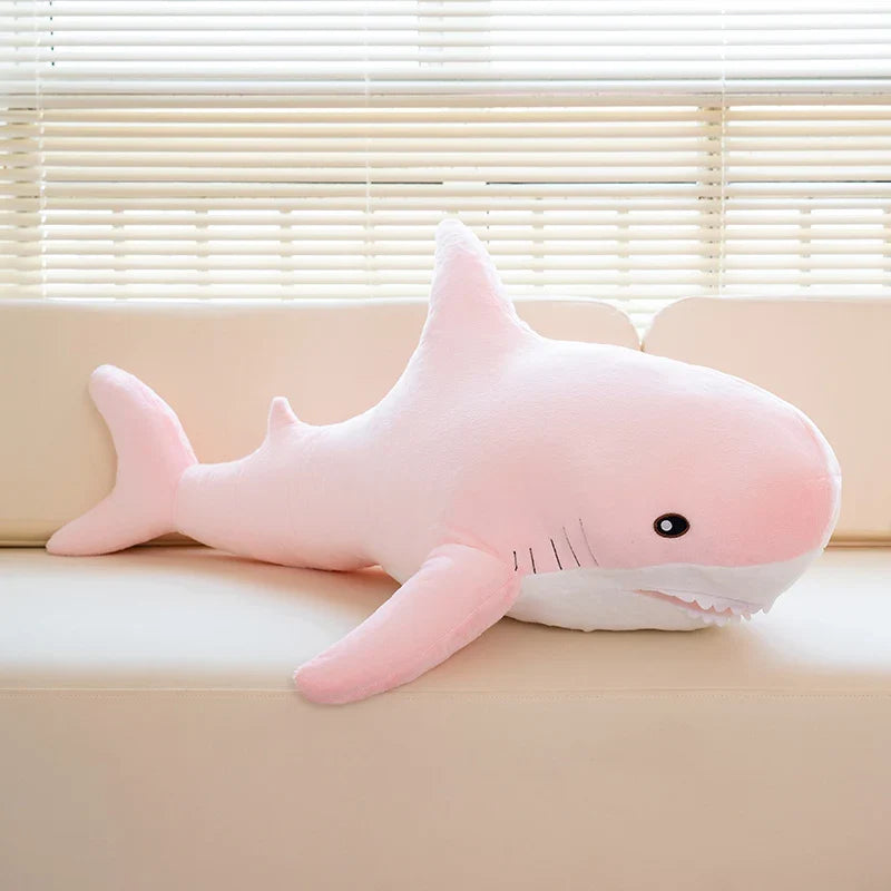 Peluche requin rose sur un canapé