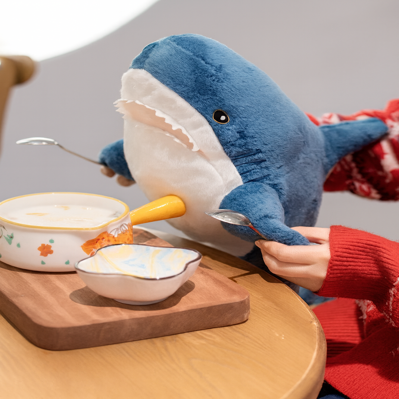 Peluche requin bleu à table tenue par une fille Image
