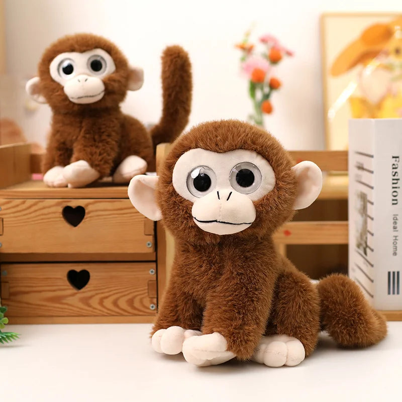 Deux peluches singes aux gros yeux, un assis sur un tiroir de meuble et l'autre assis sur une table  Image
