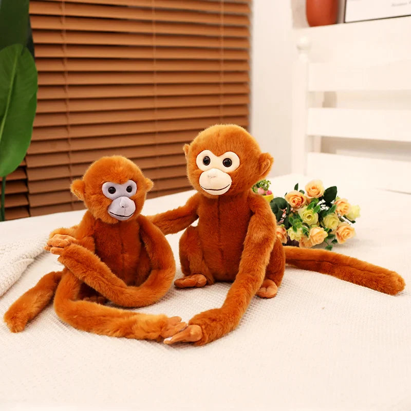 Deux peluches singes aux poils roux, un avec la tête blanche et l'autre grise sur un lit  Image