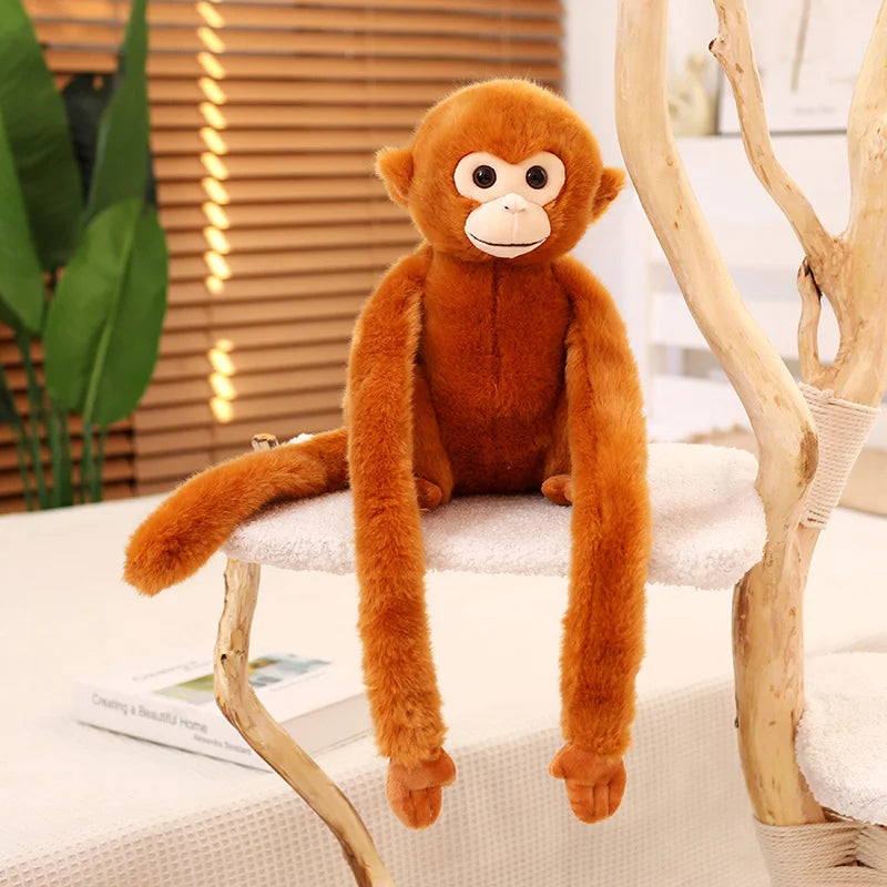 Peluche singe aux poils roux assis sur un coussin sur un arbre d'intérieur