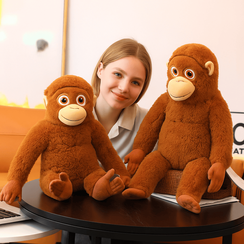 Deux peluches singes orang-outan assis sur une table avec en arrière une fille