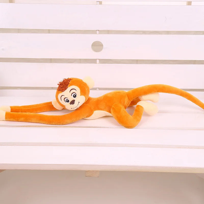 Peluche singe orange suspendu couché sur un banc Image